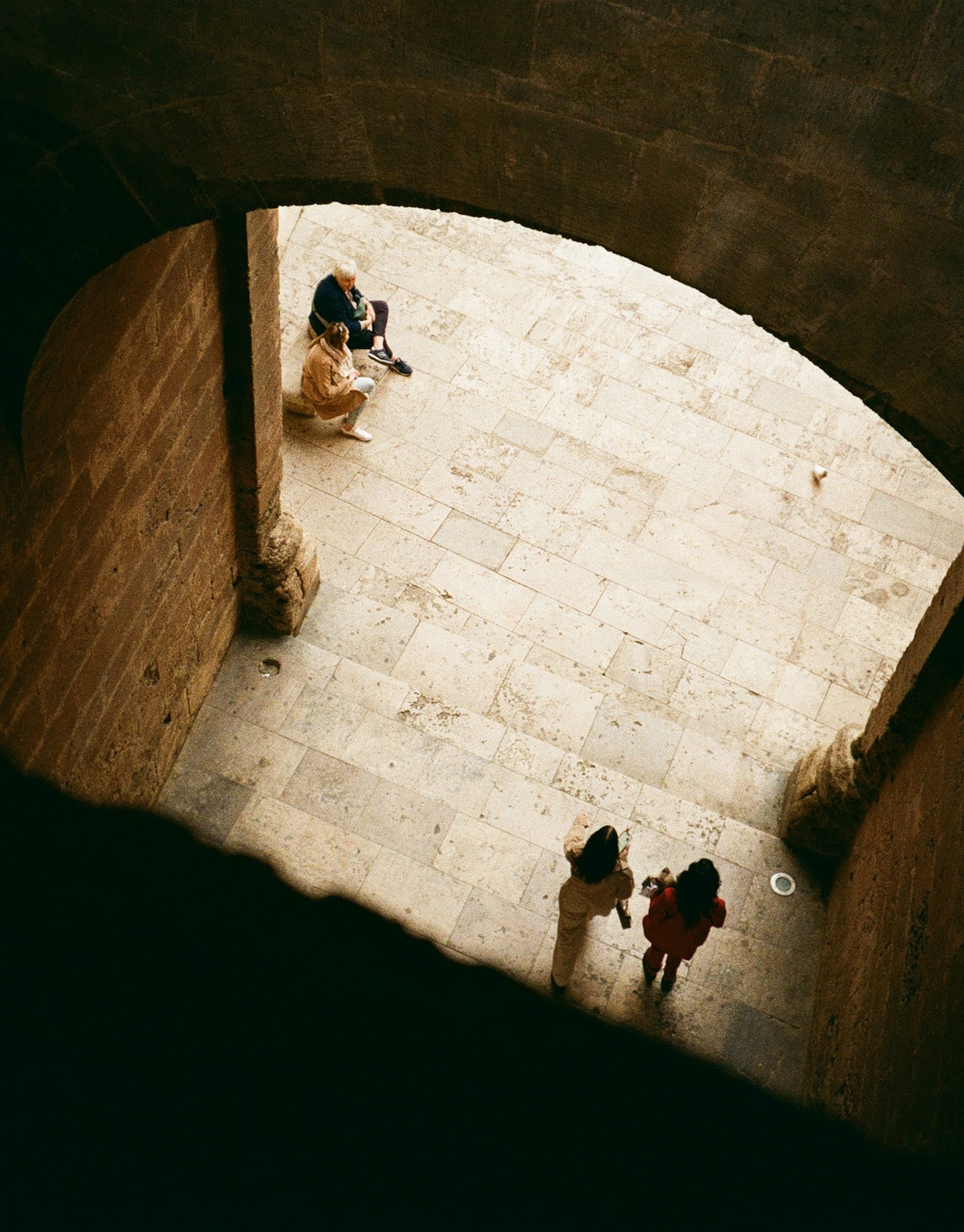 People walk on stone steps under an archway.